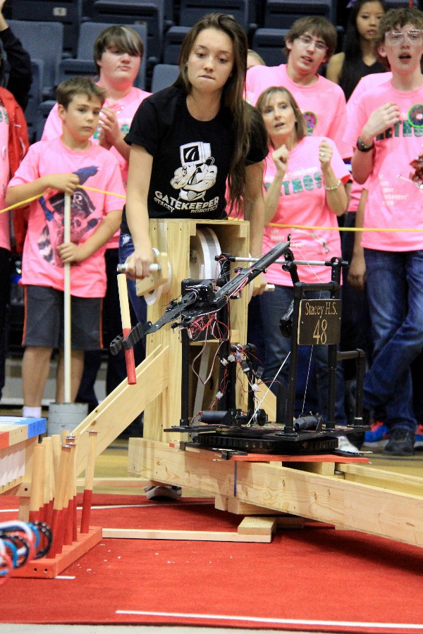 In November, Haylie D'Arrigio of Stacey High School concentrates on maneuvering her robot to pick up, grasp, and place a peg into a cup, as supporters of rival Robert E. Lee High School cheer their team on in the background.