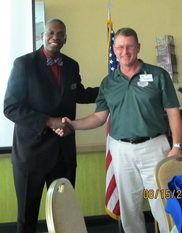 Dr. Derrick L. Tinsley (l) of Strayer University receives a chapter coin from Dan Steele, chapter president, in August.