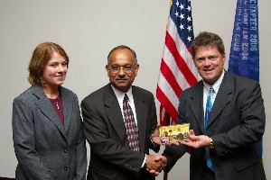 Gerald Tritle (r), chapter president, offers a gift of thanks to July guest speaker Dr. Alok Das and his representative Andrea Kunk.
