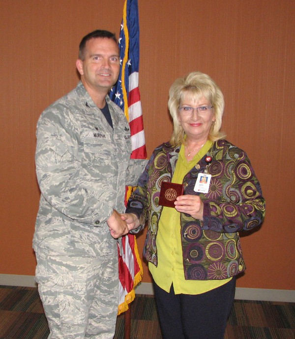 Chapter President Col. Sean Murphy, USAF, presents a chapter coin to October guest speaker, Dr. Sharon Medcalf, director and assistant professor, Department of Health Promotion, Social and Behavioral Health Center for Biosecurity, Biopreparedness and Emerging Infectious Diseases, University of Nebraska Medical Center, Omaha, Nebraska.  
