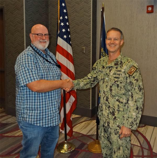 Gary Sparks, program director, Metropolitan (METRO) Community College Cybersecurity Center, Omaha, Nebraska (l), shakes hands with Capt. Thomas Merkle, USN, chapter president. Sparks was the speaker for the August luncheon and received a Greater Omaha Chapter coin for addressing the chapter.
