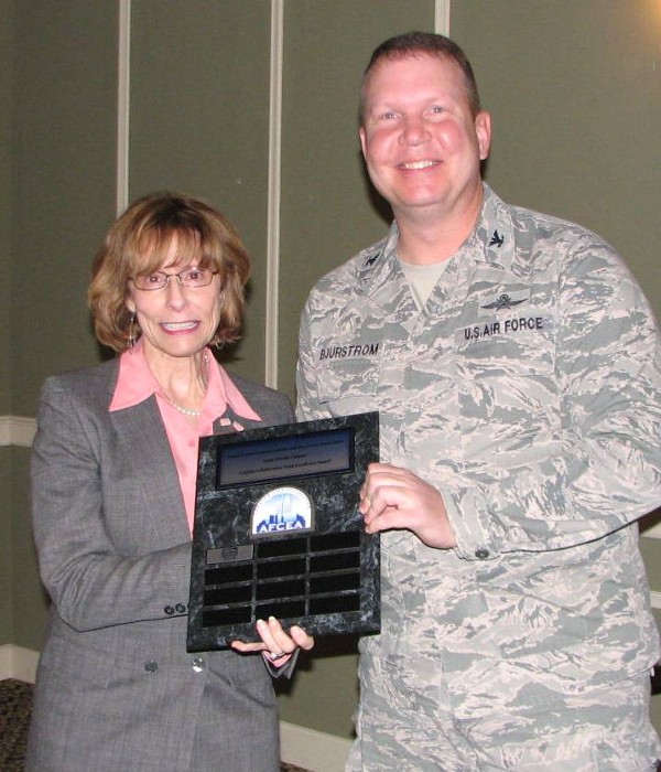 Christy Carpino (l), president, Multi-Option Systems Incorporated (MOSI), shakes hands with Col. Bjurstrom at the October meeting. MOSI is the first chapter program sponsor to receive the distinction of winning the Carpino Collaborative Team Excellence Award.