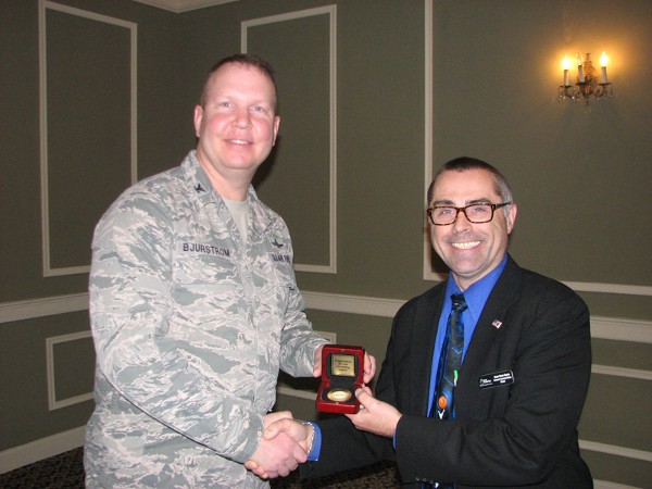 In March, Col. Bjurstrom (l) shakes hands with Danny Frisby-Griffin, program manager, GAP-CIE/ISPAN, Lockheed Martin. Frisby-Griffin received a chapter coin on behalf of Lockheed Martin for the company’s generous donation of $5,000 to boost the chapter’s scholarship fund.