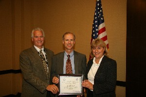 Russell L. Smith (c), CACI International, receives the Civilian Information Professional of the Month award for October from Duval. Paul von Mosch, also with CACI, nominated Smith for the award.