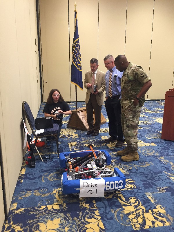 Gutierrez (far l) demonstrates the robotics team's award-winning robot to (from l) Reimers; chapter member Christopher Sweney; and Sgt. Maj. Robert Trawick, USA, at the chapter's August luncheon.