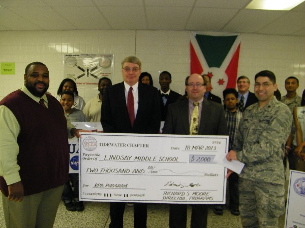 Maj. Rolando Aguirre, USAF (r), program lead for Adopt-A-School and member of the chapter's board of directors, presents a $2,000 check in April to Deon Garner (l), assistant principal of Lindsay Middle School, while industry representatives John Dahlgren and Jeff Rowell of MITRE Corporation stand by.
