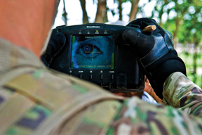 A U.S. paratrooper uses a handheld identity detection device to scan an Afghan man's iris while on patrol in Afghanistan's Ghazni province.
