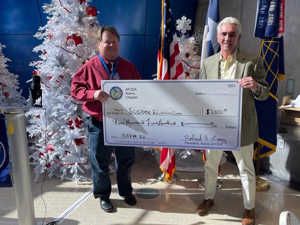 Christopher "Pup" Lyon, chapter vice president of scholarships and educational grants (r), presents Richard Varner, center director, Scobee Education Center, a $2,500 check for the Scobee Education Center's STEM programs.