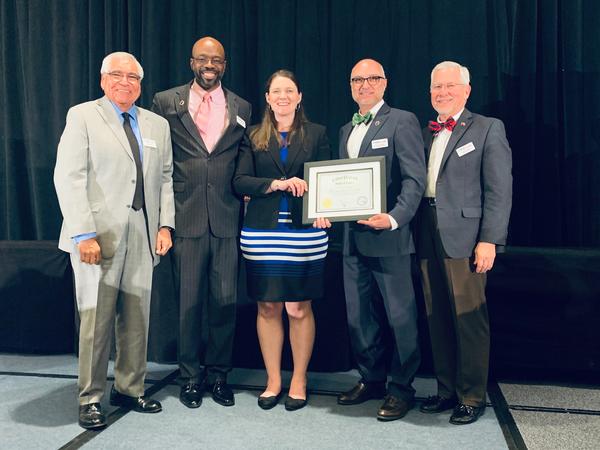 Rachel Zimmerman, director of business operations and deputy commissioner for CyberPatriot (c), presents the CyberTexas Foundation team, (from l-r) Dan Cruz, Victor Malloy, Joe Sanchez and Chris Cook, with the first CyberPatriot Hall of Fame certificate during the 10th anniversary of the San Antonio Mayor's Cyber Cup in February.