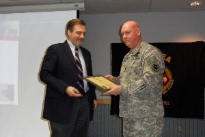 Lt. Col. Mike Brown, USA (r), chapter president, presents a corporate membership certificate to Brad Spees, vice president for network access services, GCI, at the January meeting.