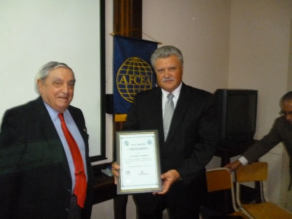 In August, Eduardo Martino (r), superintendent of communications and technical services, Metropolitan Police, receives a Distinguished Membership Award from Adm. Nigoul.