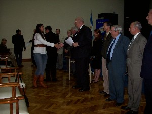 In April, Schneider presents a certificate to a meeting attendee.