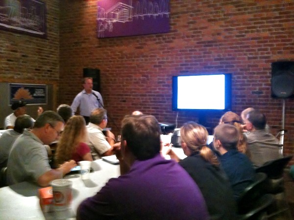 Scott Vines of Logic Nation speaks to government and industry information technology professionals while demonstrating common hacker techniques at the chapter's first Continuing Education Lunch and Learn hosted by CoHabitat in Shreveport, Louisiana, in June.
