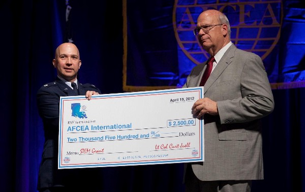Kent Schneider (r), president and chief executive officer of AFCEA International, accepts a $2,500 check from Col. Juell in April as a contribution to the Educational Foundation's grants for science, technology, engineering and mathematics.