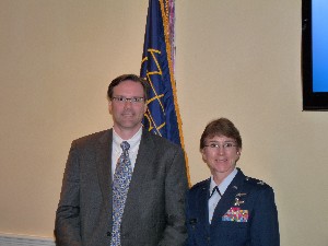 Timothy J. Magner, a fellow with Education Impact, accepts a token of appreciation for his speech from Col. Tracy Phillips, USAF, chapter president, at the July luncheon.