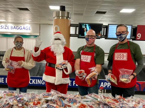 Sgt. First Class Chuck Schara, Santa, and chapter "elves," including Paul Wertz, chapter president, and Chris Bloor, participate in the USA's Holiday Block Leave and the Region IV United Service Organization handing out Christmas snacks to thousands of Fort Gordon troops as they transit through the Hartsfield-Jackson International Airport. 