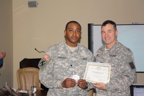 In March, Specialist Shannon Haynes (l), ANG, receives a certificate and commemorative AFCEA coin from Col. Mark Powell, USA, chapter executive vice president, in recognition of his superior efforts during the January “Snowmageddon,” easing the crisis for thousands of stranded motorists.