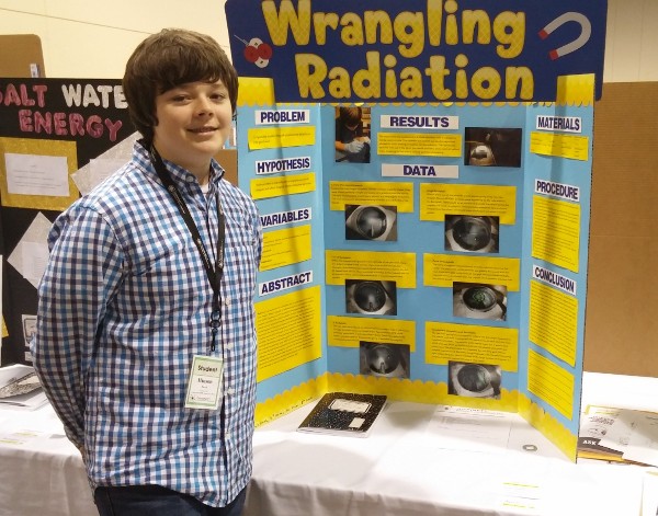 Jacob Hinson stands next to his middle school science project that demonstrates the ability to magnetically detect, capture and divert radioactive Alpha particles at the 2016 Gwinnett County Regional Science, Engineering and Innovation Fair in February.