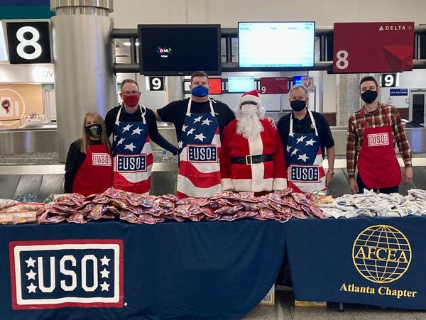 In December, (from l-r) Sandra Daniels, Chris Bloor, Kurt Schmid, David Landry, Santa and Chandler Harris prepare to dispense goodie bags to 2,000 troops headed home for the holidays.