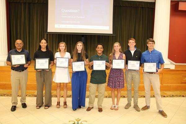 The Augusta-Fort Gordon 2019 Scholarship winners (l-r) Robert Morris, (accepted on his behalf by his father), Monique Porter, Kacie Abney, Sara Gregory, Kaleb Worku, Rachel Hammersfahr, Zack Burkhardt, and Abram Coleman, receive their awards at the July event. All are outstanding future STEM leaders. 