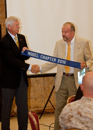 Dave Grundies (l), regional vice president, presents Paul Wickstrom, chapter vice president, with the chapter's 2010 Model Chapter banner at the July luncheon.
