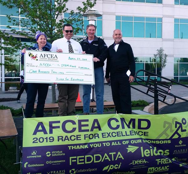 Jessica Morgenstern, chapter scientific education vice president; Martin Barrett, immediate past chapter president; Roger Crone, CEO, Leidos; and Bob Mullen, chairman, Race for Excellence, present a check to the chapter's STEM scholarship fund at the April event.