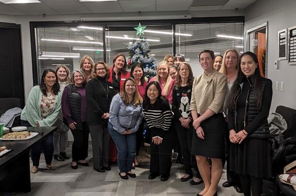 (l-r) Stewart, Laurie Beatty, Miller-Jones, Sarah Kwak Yi, Amy Rau, Kelly Proia, Tiffany Tong, Amy Fanning, Sarah Barker, Michael, Sarah Kesselring, Nancy Chrisman, Jan Tyree, Amy Monroe, Katelyn Koo, Alisha Judkins and Laura Smith gather for a photo at the December event.