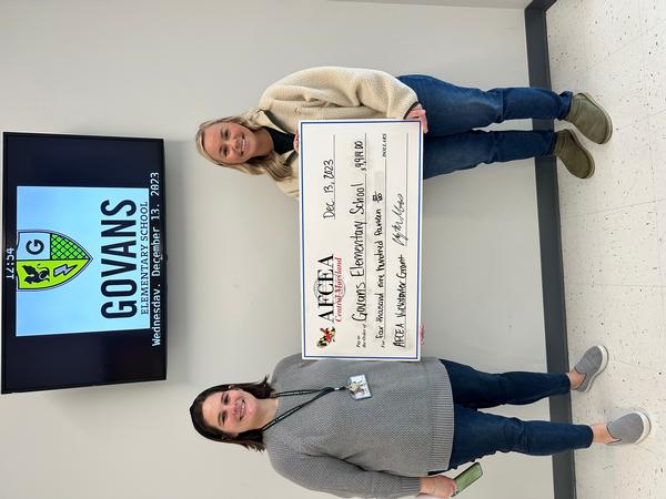 In December, Rebecca Wheeler (l) and Elizabeth Haroth hold up the grant check given to Govans Elementary School in Baltimore.