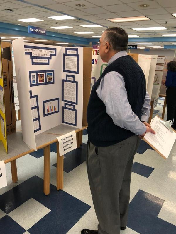 Volunteer John Garcia studies a student's analysis of protein snack nutrition at the December science fair.