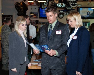 Brian Osborne, Young AFCEAN chairman, welcomes two Young AFCEANs to the March networking event.
