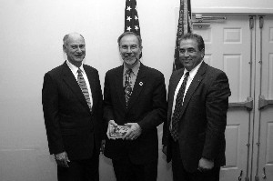 Thomas S. Wells (c), a member of the Senior Executive Service, director of contracting, Headquarters Air Force Materiel Command, Wright-Patterson Air Force Base, Ohio, receives a gift of appreciation, from Chapter President Dennis Doucet (l) and Michael Bridges for speaking at the luncheon.
