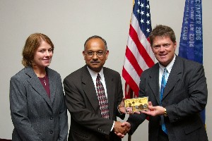 Gerald Tritle (r), chapter president, offers a gift of thanks to July guest speaker Dr. Alok Das and his representative Andrea Kunk.