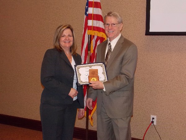 Jerald L. Straw, unmanned aircraft systems lead, Air Force Research Lab, and the analyst test bed lead, 711th Human Performance Wing, receives a print of a Wright B Flyer from Linda Skinner, chapter president, following Straw's speech at the July luncheon.