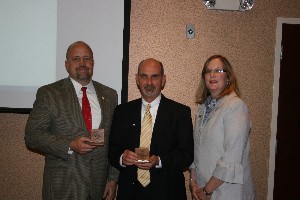 Whittaker (r) presents David Hart (l), former chapter president, and Dan Curtis, chapter vice president for programs, with AFCEA coins in May.