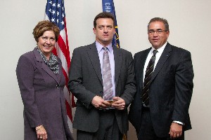 Michelle Corcoran, chapter president for 2008, presents Richard Reed (c), Air Force Materiel Command, with a Wright Brothers Flyer coin set, while Michael Bridges, vice president of programs, looks on.