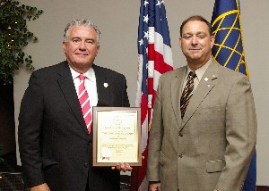Norman Nelson (r), chapter membership vice president, presents John Clark, president of The Whitestone Group-U.S., with a plaque commemorating his company as a new corporate member. 
