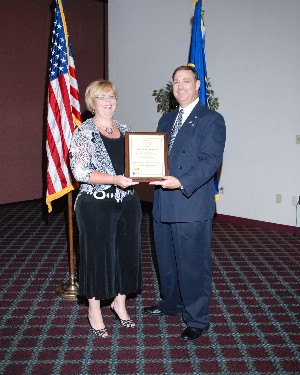 Nelson presents Beth Brown, relationship manager for Illumination Works LLC, with the company's corporate membership plaque at the May meeting.