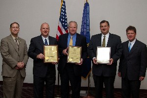 Norman Nelson (l), chapter corporate vice president, presents new corporate membership plaques to (2nd from l-2nd from r) Jeffrey VanFleet, Lighthouse Technologies; Christopher S. Pfeifer, McNamee and McNamee PLL; and George Satornino, Sierra Lobo Incorporated, while Tritle looks on.
