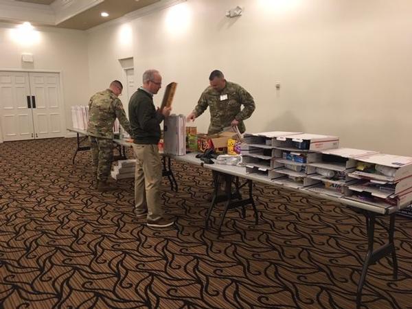 Col. Roberto R. Castillo, USA, and event attendees prepare care packages for deployed Soldiers at the December event.