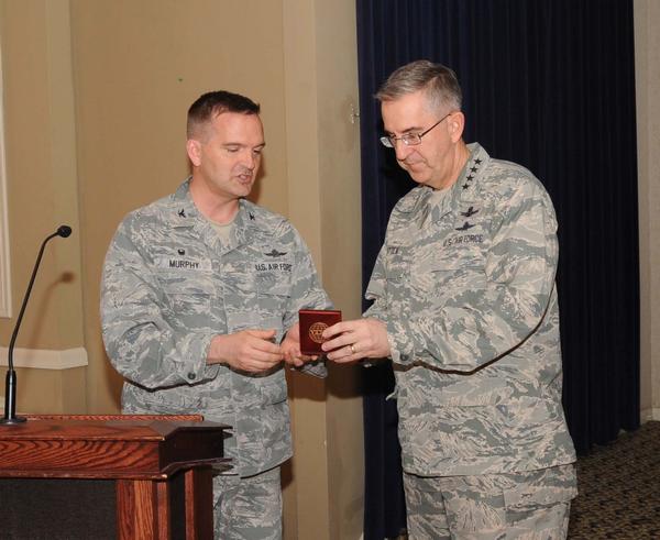 Chapter President Col. Sean Murphy, USAF (l), presents April guest speaker Gen. John E. Hyten, commander, U.S. Strategic Command (STRATCOM), Offutt Air Force Base, Nebraska, a chapter coin as a token of thanks. 