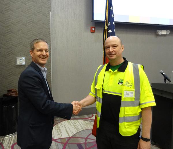 Thomas Merkle, chapter president (l), shakes hands with Isaac Piper, instructor of technology experiences, Applied Information Management Institute, Omaha, Nebraska. Piper was the speaker for the May luncheon and received a Greater Omaha Chapter coin for addressing the chapter.
