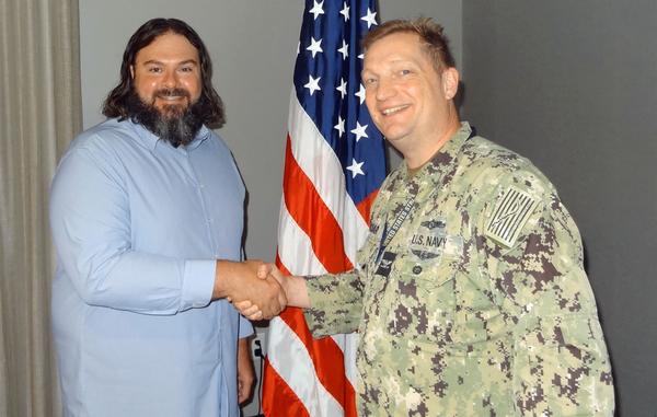 Eric Reichwaldt, co-founder and executive director, Shyft Solutions, Omaha, Nebraska, shakes hands with Capt. Brad Melichar, USN, chapter president. Reichwaldt received a Greater Omaha Chapter coin for addressing the chapter in August.