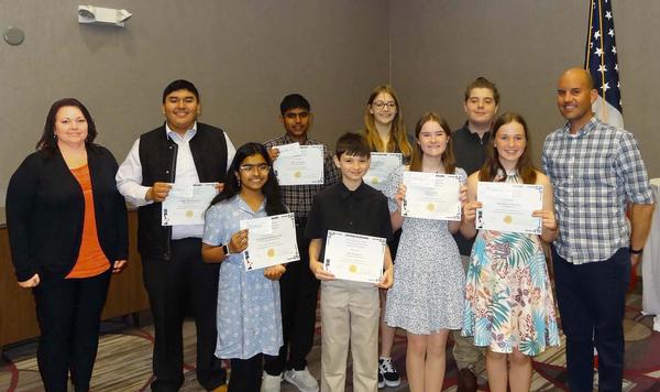 Diane Campbell, chapter vice president of academics (l), stands next to the eight award recipients from the Omaha Metropolitan Science Fair featured at the April luncheon. Students pictured (l-r) are: Edgar Del Cid Luten, Omaha South High School, Omaha, Nebraska, 11th grade, Hardware Interfacing Using LabVIEW; Aishwarya Pandharpurkar, Elkhorn Valley View Middle School, Elkhorn, Nebraska, 7th grade, A Boost of We-Fi from Parabolas; Athreya Reddy, Elkhorn Ridge Middle School, Omaha, Nebraska, 8th grade, Reemergence of Mpox: Bioinformatics Approach; Rex Mussman, Carl A. Swanson Elementary, Omaha, Nebraska, 6th grade, Look Out Below!; Laney Crinklaw, King Science  and  Technology Middle School, Omaha, Nebraska, 8th grade, Do Higher Frequencies Produce More Thermal Energy Than Lower Frequencies?; Ella Carson, Buffett Middle School, Omaha, Nebraska, 8th grade, Bridges Holding the World; Gabe Keith, Buffett Middle School, Omaha, Nebraska, 8th grade, Robo Lifting; Mackenzie Simpson, Buffett Middle School, 8th grade, Does Multitasking Suit You? Also pictured is Samuel Fischer (r), teacher, Marrs Middle School, Omaha, Nebraska, who assisted in the evaluation/selection of student projects. Projects were accessed at the Henry Doorly Zoo in March. The chapter awarded a total of $1,600.