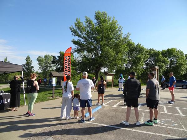 Pictured in the foreground is Janel Nelson, chapter vice president of programs, welcoming everyone to the chapter's tenth 5K and providing opening remarks to the participants of the 2026 event.  She thanked all for being there and for their continued support. Once again, Stormy, Omaha Storm Chasers Mascot can be seen as part of the assembly.