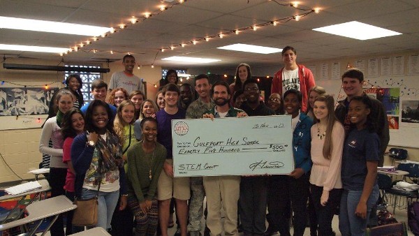 In November, Hardy Thames (front row, c), technology teacher, accepts a STEM grant from Capt. Lewis (back row, c) on behalf of Gulfport high School. Thames' third period technology class joins in for the presentation.