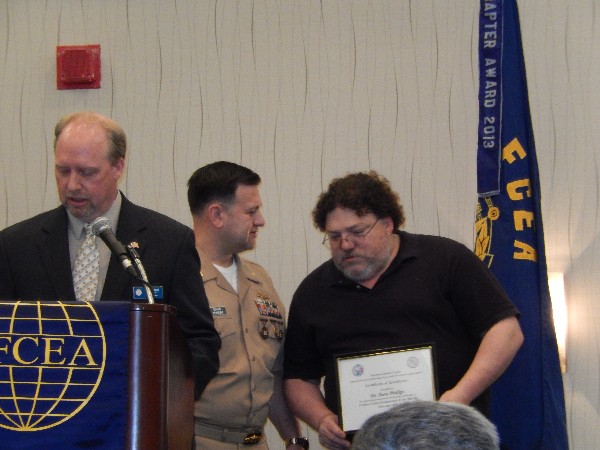 Larry Minnick (l), chapter executive vice president, and Cmdr. Pereira (c) present David Philips with the Cyber Professional of the Month Award in February.