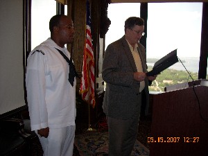 Capt. Bob Whitkop, USN (Ret.) (l), chapter president, reads a letter of commendation recognizing Petty Officer 1st Class Wally Lora, USN, as Information Professional of the Month in May.