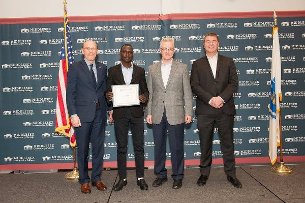Middlesex Community College President James Mabry (l), along with John Barrette, chapter vice president, education (2nd from r), and Bob Chisholm, chapter scholarship committee (r), present Sebastian Rojo with a Thomas O'Mahony Spirit of Excellence Award in March. 