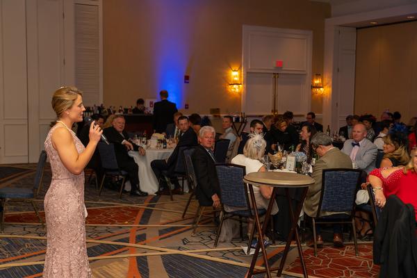 Maj. Kate Stowe, USAF, chair, spring gala committee, welcomes guests to the annual spring gala held in May, featuring live Kentucky Derby viewing and a silent auction fundraiser to support the chapter's education fund. 