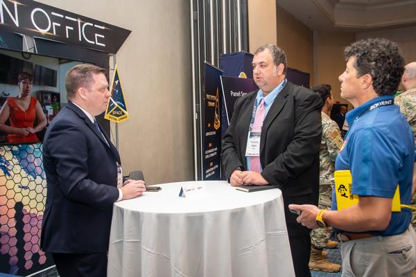 Event participants meet at the Space Systems Command program manager's booth in October.